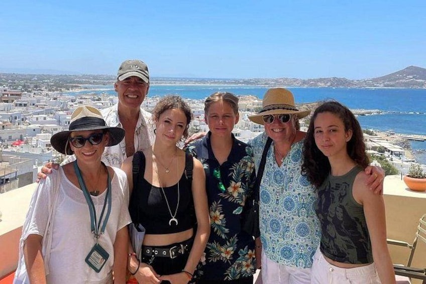En grupp människor som står på en balkong med en stadsbild och havet i bakgrunden. 3