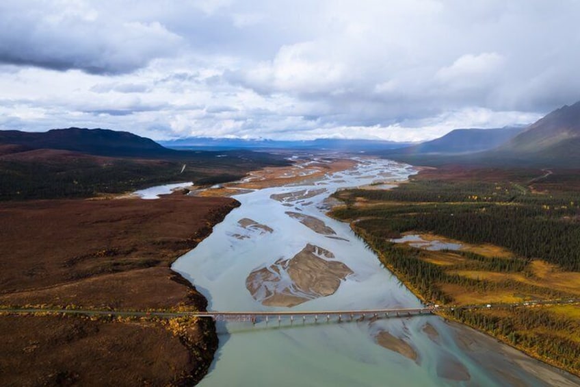 A river flowing through a valley with a bridge, surrounded by forested hills. 5