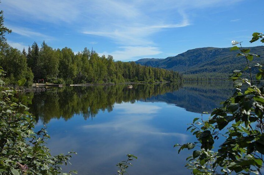 Un lac paisible, entouré d’une forêt dense et de montagnes, sous un ciel dégagé. 2