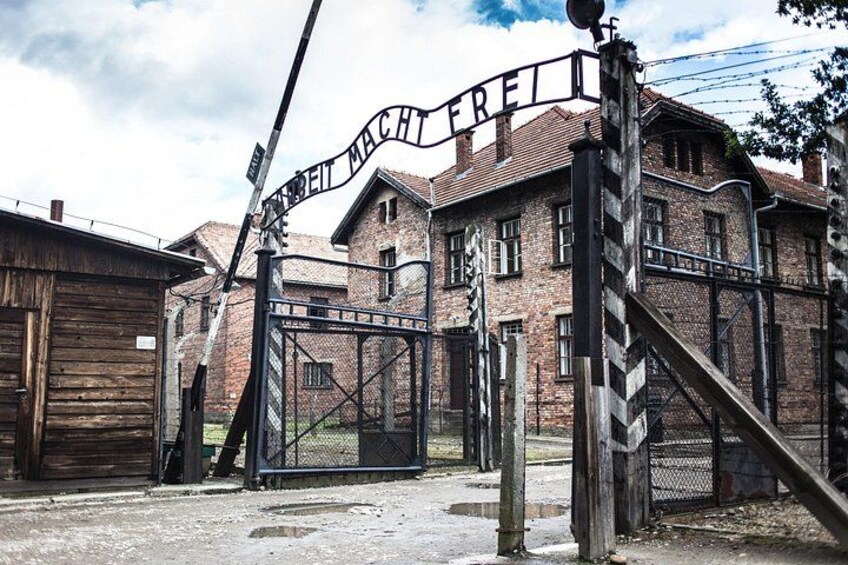 Een historisch gebouw met een groot metalen hek en een bord waarop staat 'MACHETE FREI'. 1