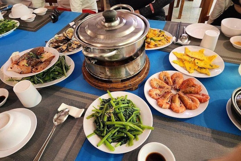 A table with various dishes, a hot pot, and dining utensils. 3