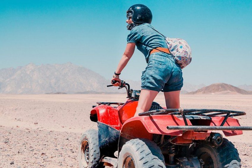 A person riding an ATV in a desert landscape with mountains in the background. 3