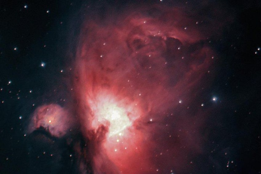 Una nebulosa con zonas brillantes de rojo y blanco, estrellas y un fondo oscuro. 5