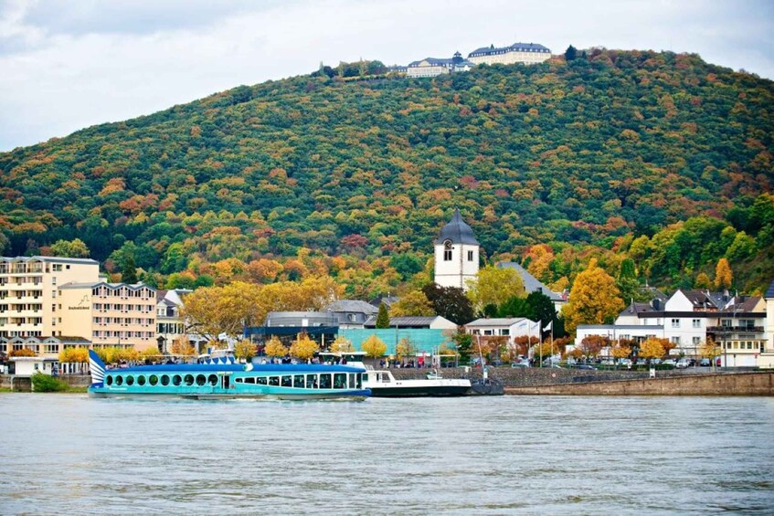 A river with a blue boat, buildings, and a hill with trees. 3