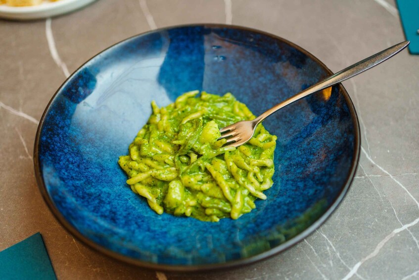 A blue bowl of pasta with a fork. 2