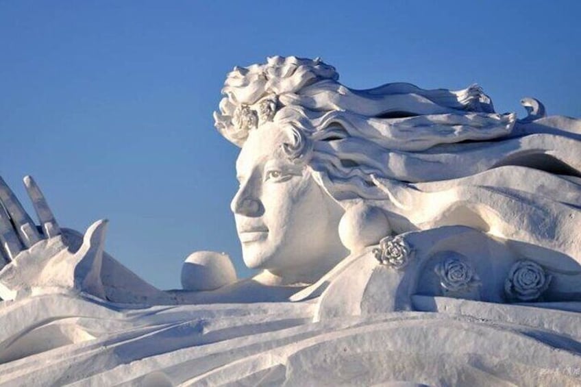 A large snow sculpture of a figure with flowing hair and a hand gesture. 5
