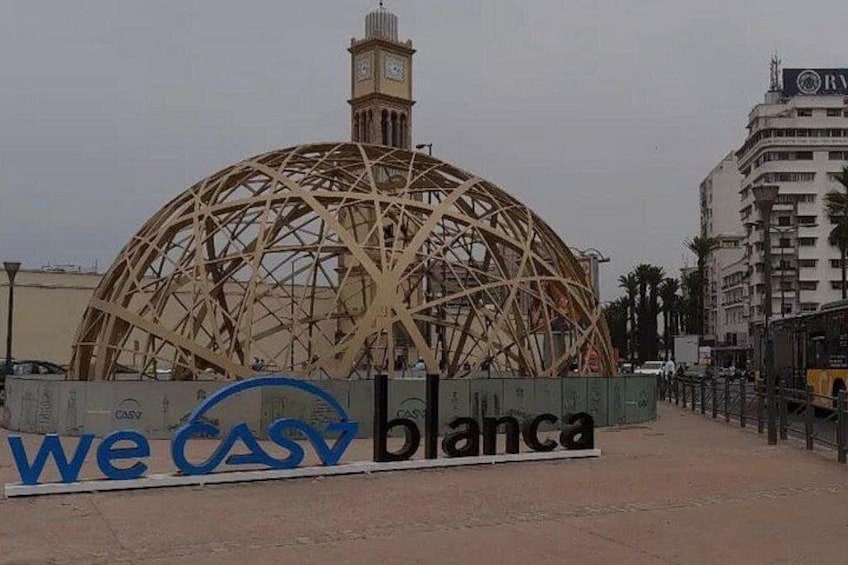A large, spherical structure with a lattice framework, a clock tower, and a sign with 'weCASY blanca' text. 2