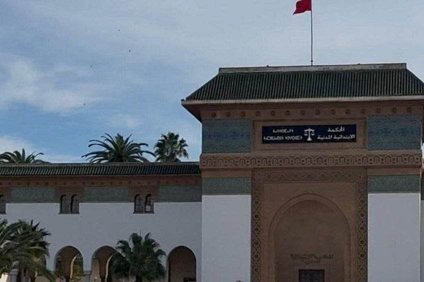 A building with a red flag, a sign with Arabic script, and a decorative archway. 3