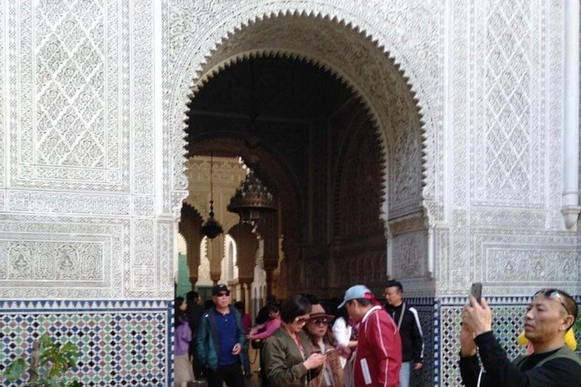 A group of people standing in front of a detailed architectural archway. 4
