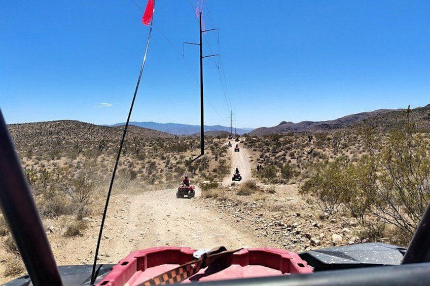 A desert landscape with a dirt road, a vehicle, and a person riding a motorcycle. 4
