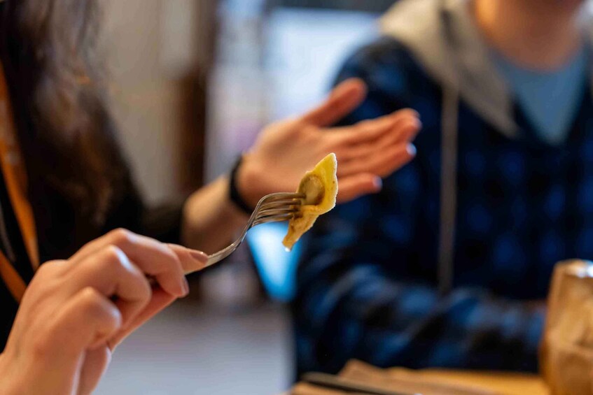 A person holding a fork with a piece of food. 3