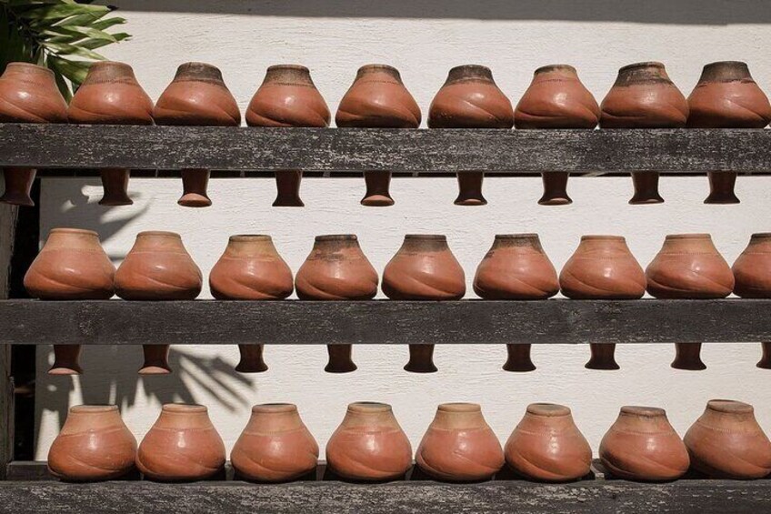 Una exhibición de macetas de terracota dispuestas en estantes junto a una pared. 4