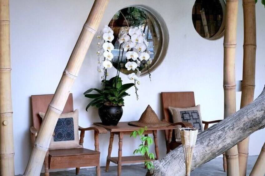 Una estructura de bambú, una silla de madera, una mesa, una planta en maceta y un espejo. 3