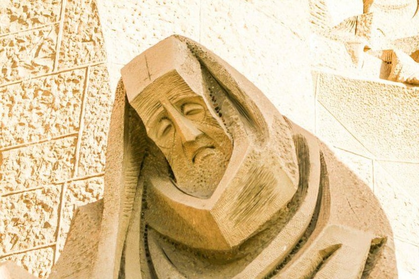 Une sculpture de sable représentant un visage coiffé d’un couvre-chef, le tout mis en valeur par un fond composé de carreaux. 3