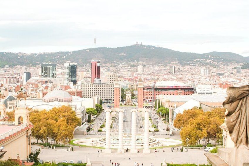 A cityscape with a prominent statue, a fountain, and a hill in the background. 2