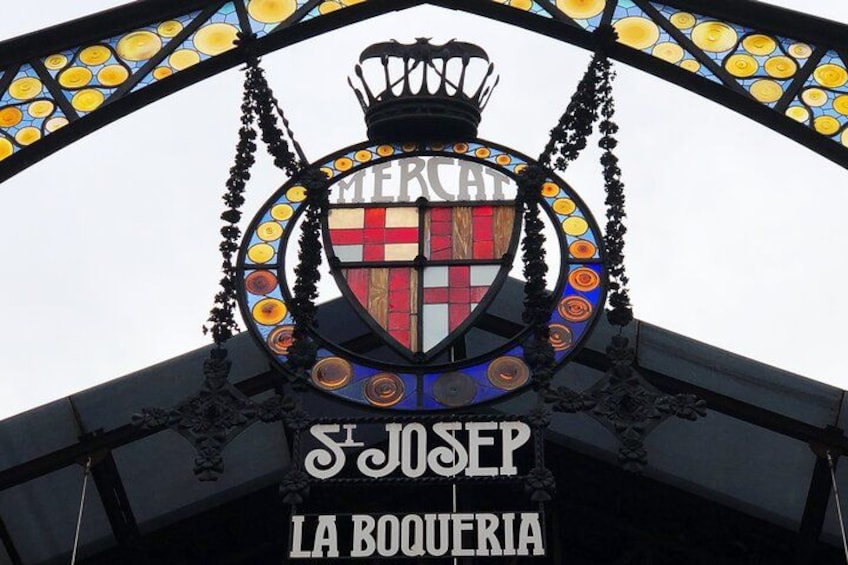 A stained glass sign with the text 'Mercat St. Josep La Boqueria' and a crown above it. 4