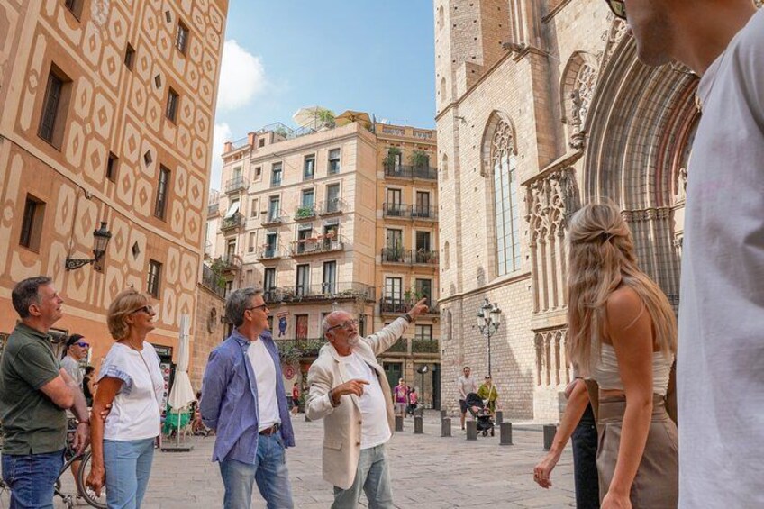 A group of people walking in a historic square with ornate buildings and a cathedral in the background. 4