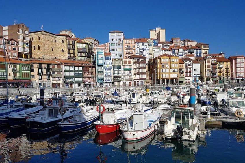 Un port de plaisance avec des bateaux amarrés, un ciel bleu azur et des bâtiments colorés en arrière-plan. 4