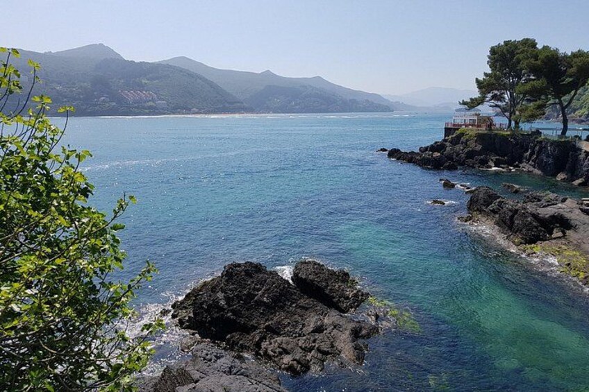 Un paysage côtier caractérisé par des eaux d’un bleu limpide, des rivages rocheux et des montagnes lointaines. 5