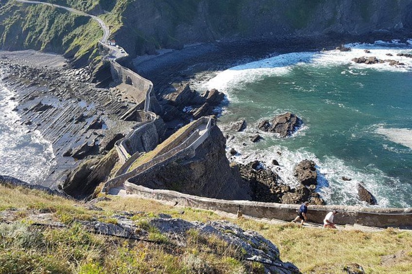 Un paysage côtier avec une route sinueuse, des falaises rocheuses et une étendue d’eau. 2