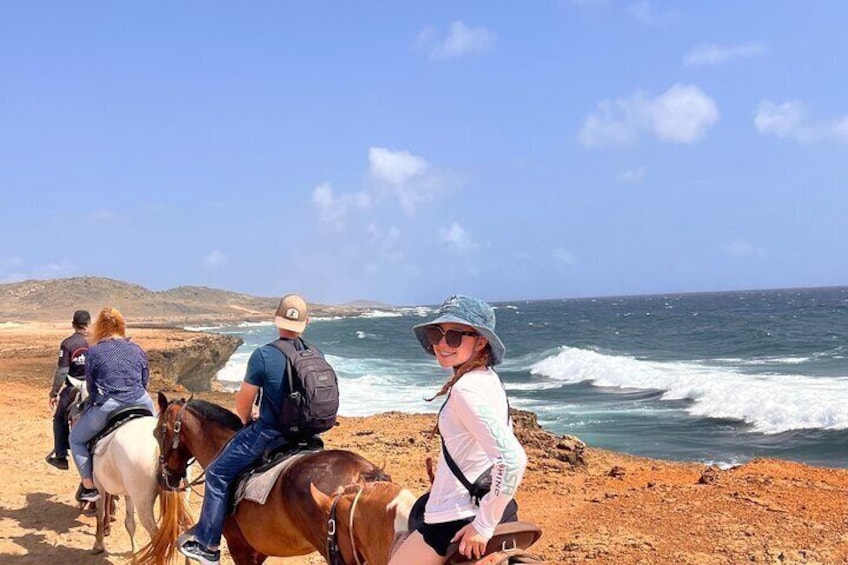 Menschen reiten entlang eines Küstenpfades mit dem Ozean im Hintergrund. 1
