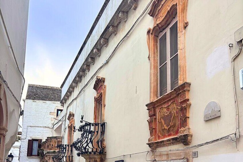 A narrow street with ornate window frames and a sign reading "Le Morillon." 3