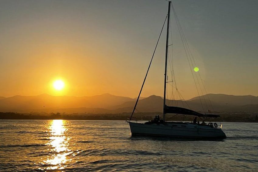 A sailboat on calm water during sunset with mountains in the background. 5