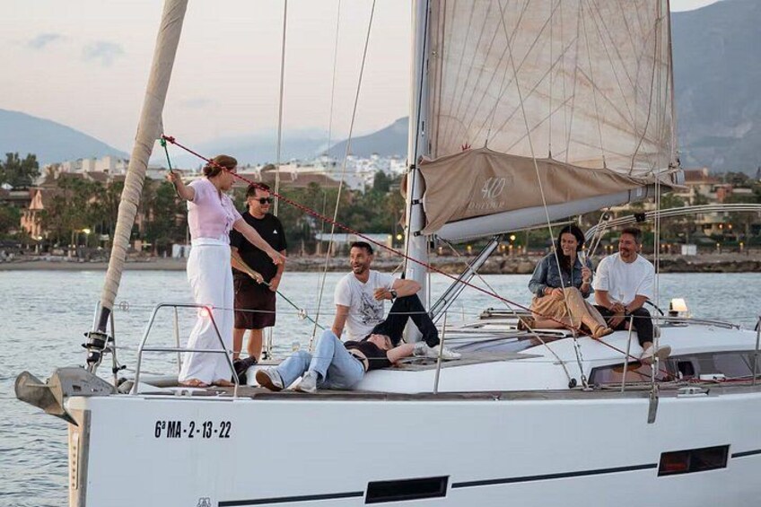 A sailboat with people on board, a cityscape in the background, and a body of water. 2