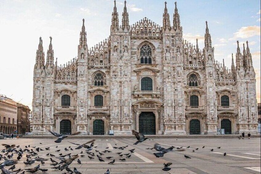 A Gothic cathedral with intricate architecture and a large open plaza with pigeons. 2