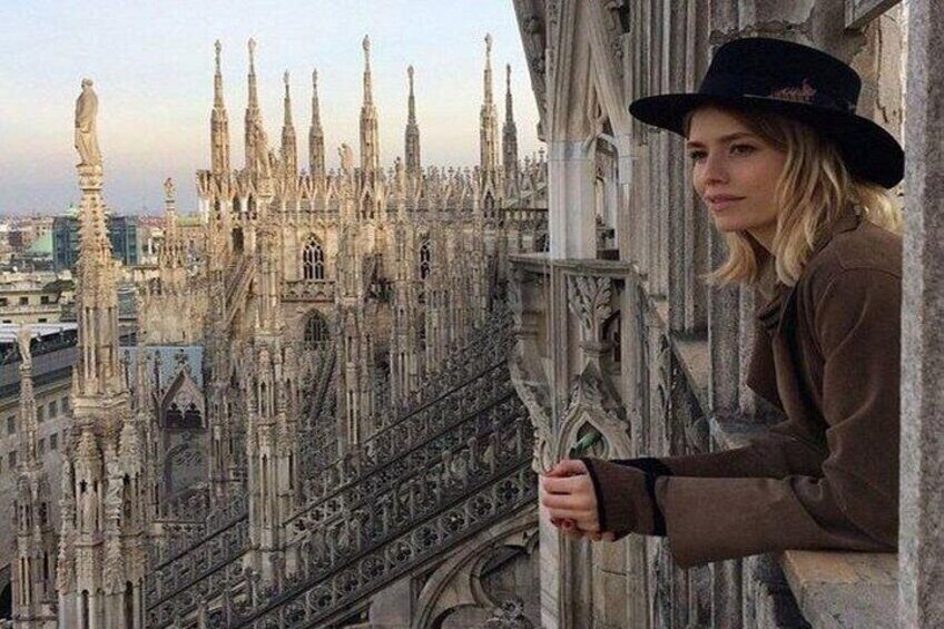 A person leaning on a stone balustrade overlooking a Gothic cathedral with intricate spires and detailed stonework. 1