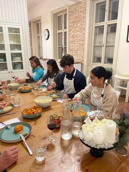 A group of people dining at a wooden table with various dishes and drinks. 2