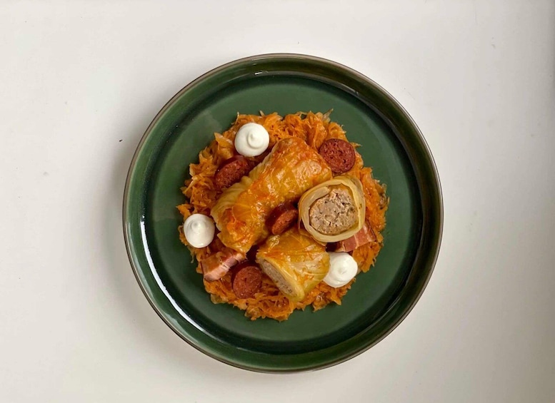 A plate of stuffed cabbage rolls with sausage and a dollop of sour cream. 5