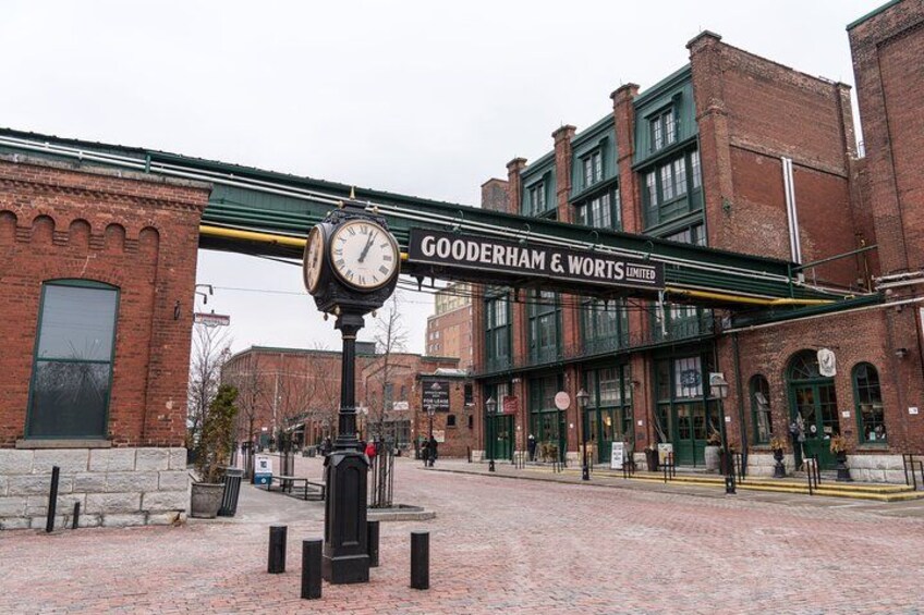 A clock, Gooderham & Worts Limited building, and brick pavement. 1