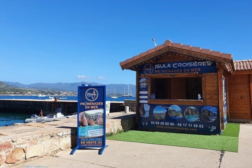 A wooden kiosk named 'Isula Croisiere's' with a signboard advertising 'PRIMENADES EN MER' and a website URL. 1