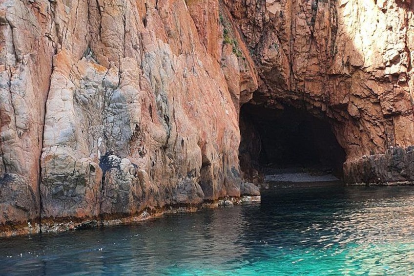 A natural rock formation with a cave entrance and clear blue water. 4