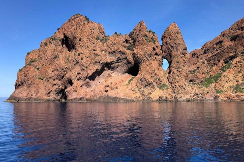 Un litorale roccioso con una grande formazione simile a una grotta e acque calme. 2