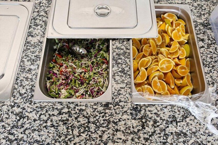 A buffet with two open serving trays, one containing sliced oranges and the other with a salad. 5