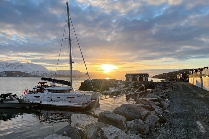 A sailboat docked at a pier with a sunset in the background. 5