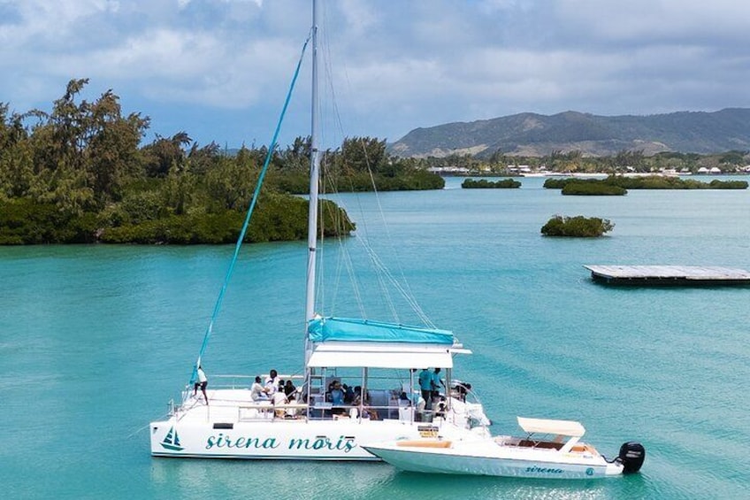 A sailboat named 'sirena mortz' on turquoise waters with a forested island in the background. 1
