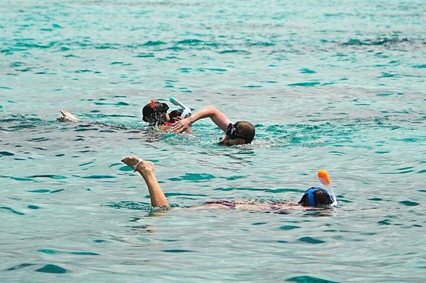 Three people swimming in the ocean. 4