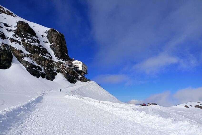 Sentiero innevato in montagna, con affioramenti rocciosi e cielo sereno. 4