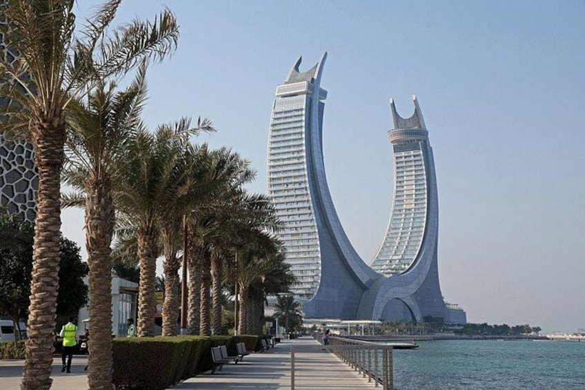 A waterfront promenade with palm trees and a distinctive curved building. 5