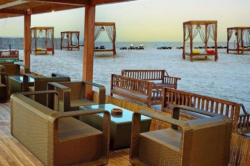 A beachside lounge with wicker furniture and a view of the ocean. 4
