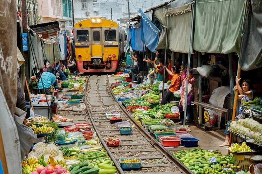 A train on tracks through a market with vendors and customers. 2