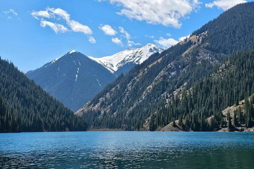 A lake surrounded by mountains with snow-capped peaks and dense forests. 5