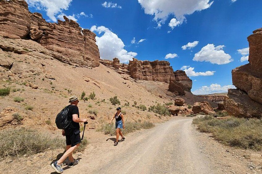 A dirt road in a rocky canyon with hikers. 4