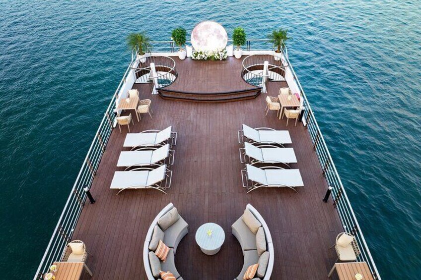 Un pont ensoleillé avec des chaises longues et un espace salon central sur un bateau. 2