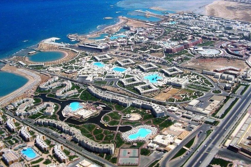 An aerial view of a coastal resort with multiple swimming pools, roads, and beachfront areas. 3