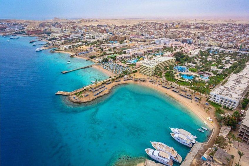 A coastal cityscape with a marina, clear blue waters, and a mix of residential and commercial buildings. 2