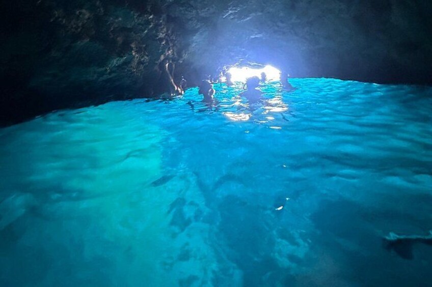 Une grotte avec une eau d’un bleu cristallin et une source de lumière au fond. 1